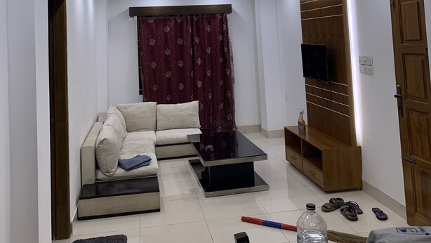 A modern living room with a sofa, a coffee table, a TV, and a ceiling fan. - Captivating 2-bed Apartment in Dhaka (Dhaka)