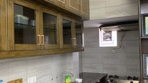 A kitchen with wooden cabinets, a stainless steel sink, a gas stove, and a tiled backsplash. - Captivating 2-bed Apartment in Dhaka (Dhaka)