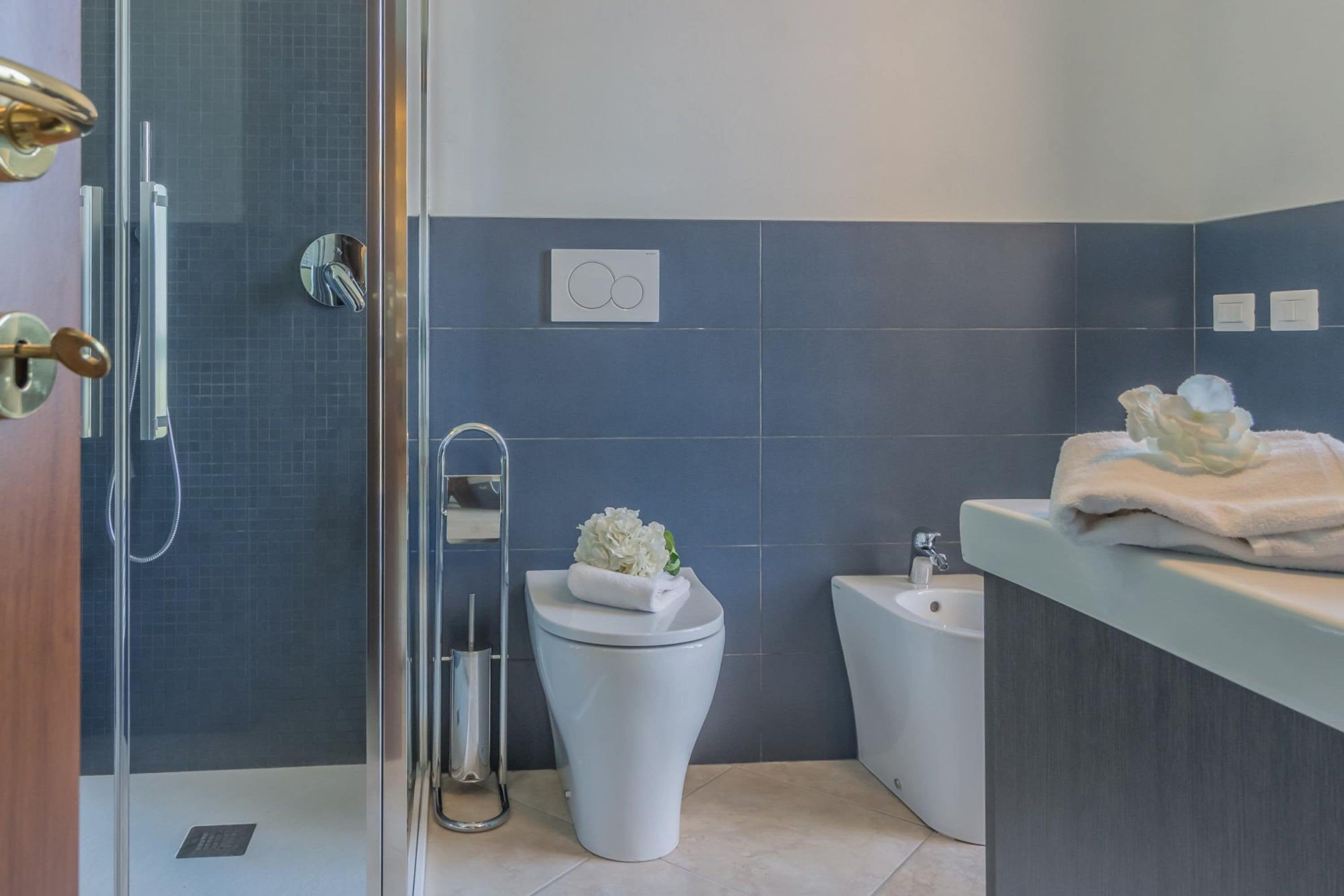 Ein modernes Badezimmer mit Dusche, Toilette, Bidet und Waschtisch mit Handtüchern.