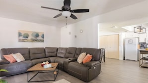 A modern living room with a sectional sofa, a coffee table, and a ceiling fan. - Cozy 3 bed 2 baths in middle Glendale (Phoenix)