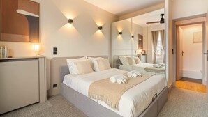 A modern hotel room with a large bed, bedside tables, a desk, and a mirror.