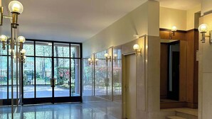 A spacious lobby with a polished floor, large windows, and a staircase leading to an upper level.