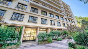 A multi-story hotel with a beige facade, large windows, and a well-maintained garden area.