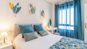Un dormitorio ordenado con cama, mesita de noche, cómoda y ventana con cortinas.