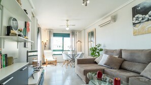 Una sala de estar moderna con un sofá, una mesa de centro de vidrio y un comedor con sillas y una mesa.