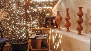 A room with a textured wall, a wooden table, a chair, and terracotta pots. - Boulenc Bed and Bread (Oaxaca)