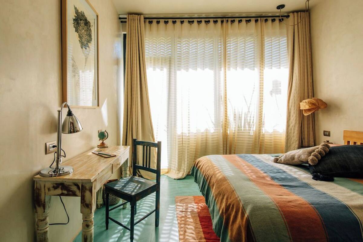 A bedroom with a bed, a desk, a chair, and a lamp.