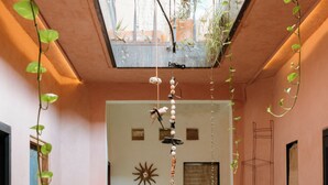 A staircase with a wooden railing, a black and orange bench, and hanging plants. - Boulenc Bed and Bread (Oaxaca)