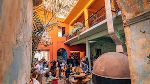 A bustling indoor space with a high ceiling, a large grill, and a balcony overlooking the area. - Boulenc Bed and Bread (Oaxaca)