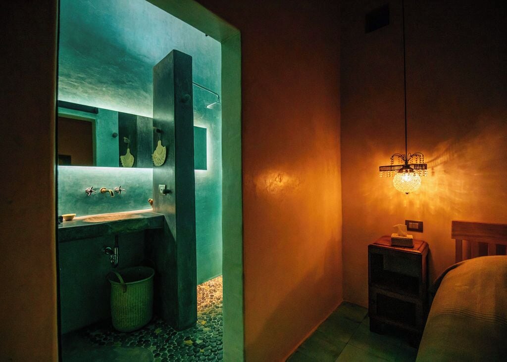Een badkamer met een moderne wastafel, spiegel en een klein nachtkastje met een lamp.