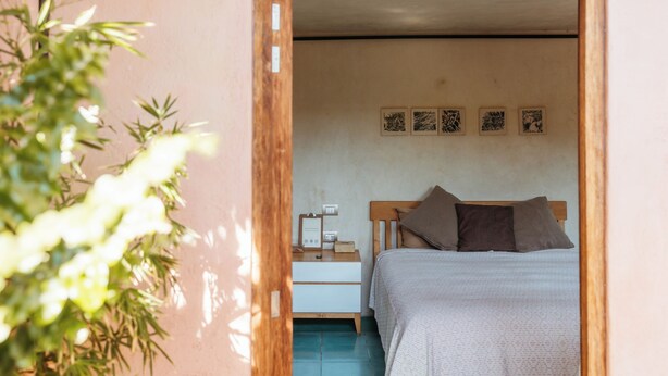 A bedroom with a bed, a nightstand, and a wall-mounted shelf. - Boulenc Bed and Bread (Oaxaca)