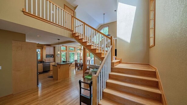Un interior amplio con una escalera de madera, una cocina y un comedor.