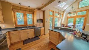 Una cocina moderna con armarios de madera, un lavamanos de acero inoxidable y una isla grande con microondas.