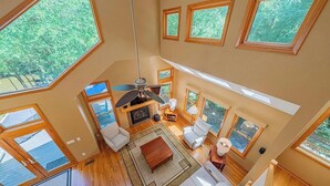 Una sala de estar amplia con chimenea, varias zonas de estar y ventanas grandes que ofrecen vistas al exterior.