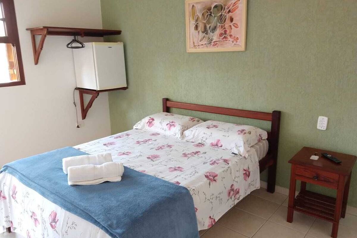Uma cama com roupa de cama florida, um cobertor azul e duas toalhas.