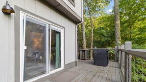 A wooden deck with a sliding glass door leading to a room with a lamp, a chair, and a small table. - Minutes to Banner Elk, Quiet MTN Home w/ Fireplace (Banner Elk)