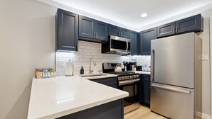 A modern kitchen with dark cabinets, a stainless steel refrigerator, a microwave, and an oven. - Minutes to Banner Elk, Quiet MTN Home w/ Fireplace (Banner Elk)
