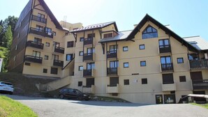Un hotel de varios pisos con balcones, un estacionamiento y un cielo despejado.