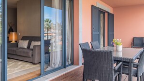 Ein modernes Wohnzimmer mit einer Couch, einem Esstisch mit Stühlen und einer Schiebeglastür, die auf einen Balkon führt.