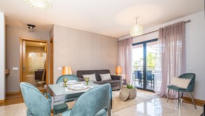 Ein modernes Wohnzimmer mit Essbereich, einer Couch und einem Balkon mit Vorhängen.