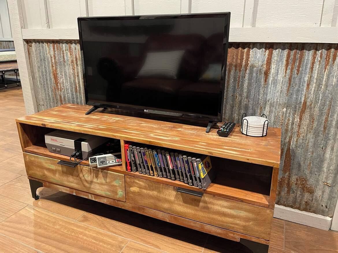 A wooden entertainment center with a flat-screen TV, a remote, and a collection of video games.