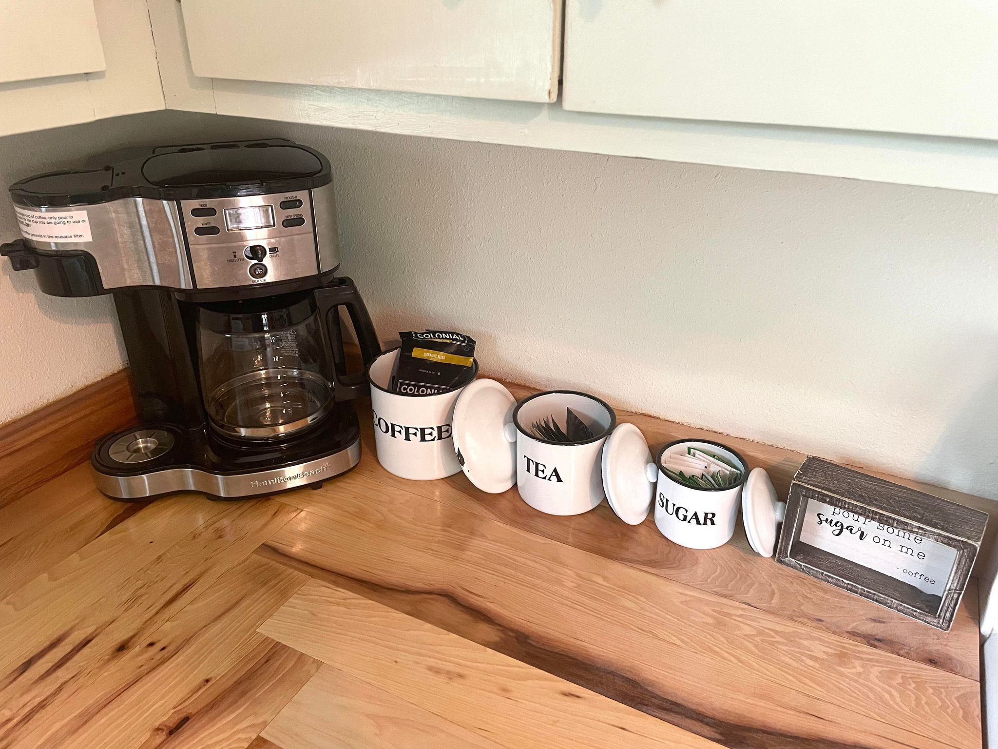 Eine Kaffeemaschine, Kaffeekapseln und Kaffeetassen auf einer Holzauskład.