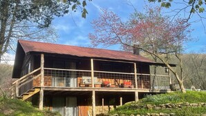 Un rustico chalet con una veranda in legno e un muro di pietra antistante.