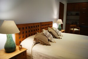 A neatly made bed with pillows, a wooden headboard, and two bedside tables with lamps.