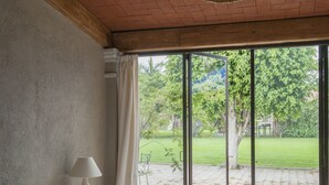A bedroom with a large bed, a hanging lamp, and a view of a garden through a sliding glass door. - Casa Quinta Mar Casa de campo en el Tule (Santa Maria del Tule)