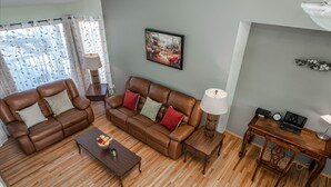 A living room with a brown leather sofa, a coffee table, and a wooden desk with a lamp. - Entire large house! 8 bedrooms & 4Baths! Close to airport! (Calgary)
