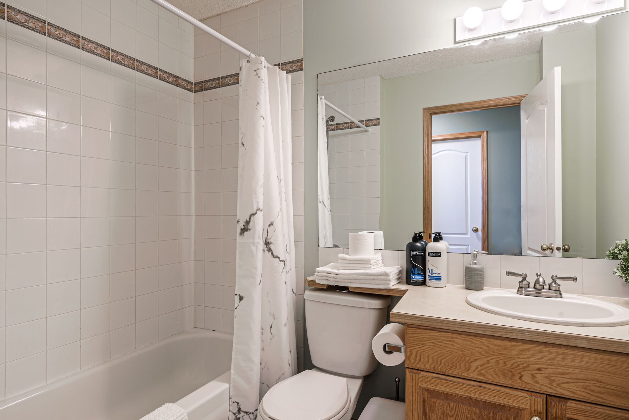 Une salle de bain avec une baignoire, des toilettes et un lavabo. On trouve des articles de toilette sur le comptoir du lavabo.