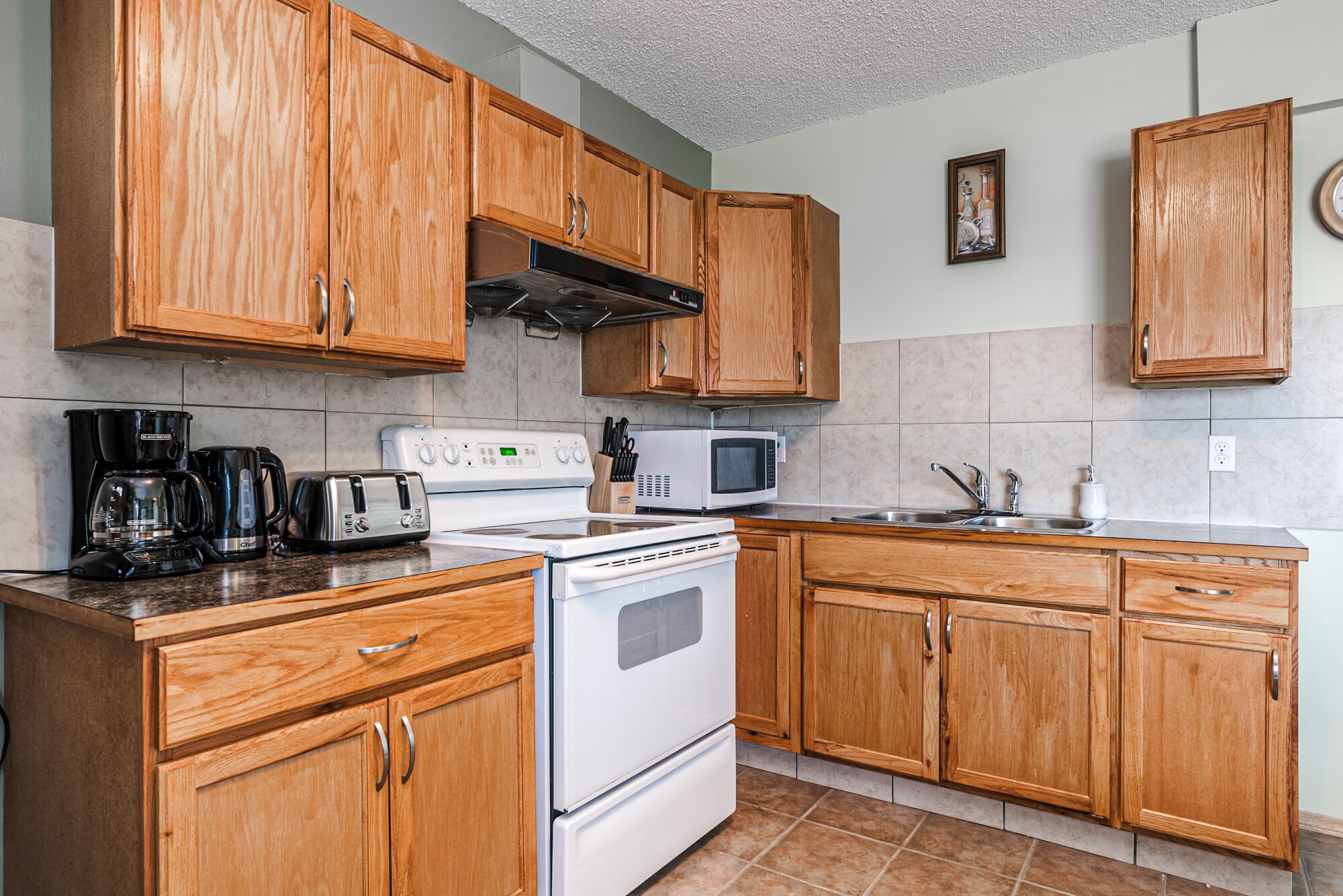 Una cocina con gabinetes de madera, estufa, microondas y cafetera.