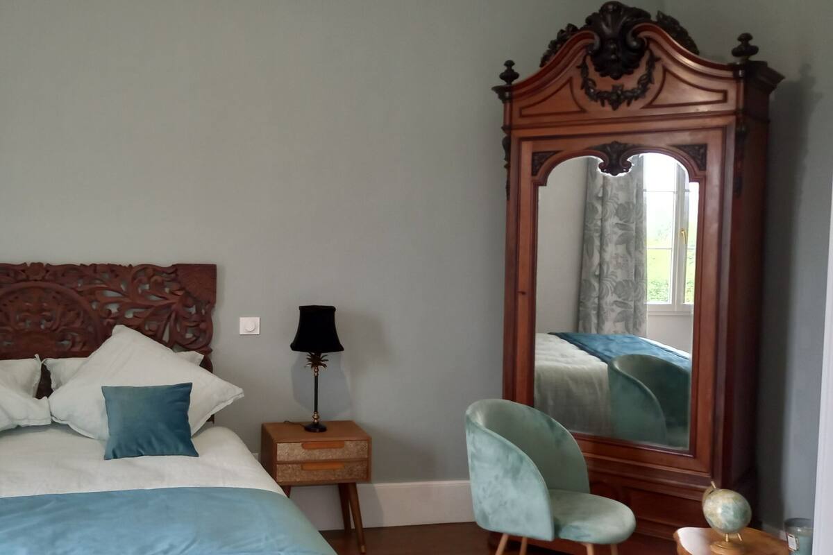 Une chambre à coucher avec un grand lit, deux tables de chevet, un miroir et une chaise.