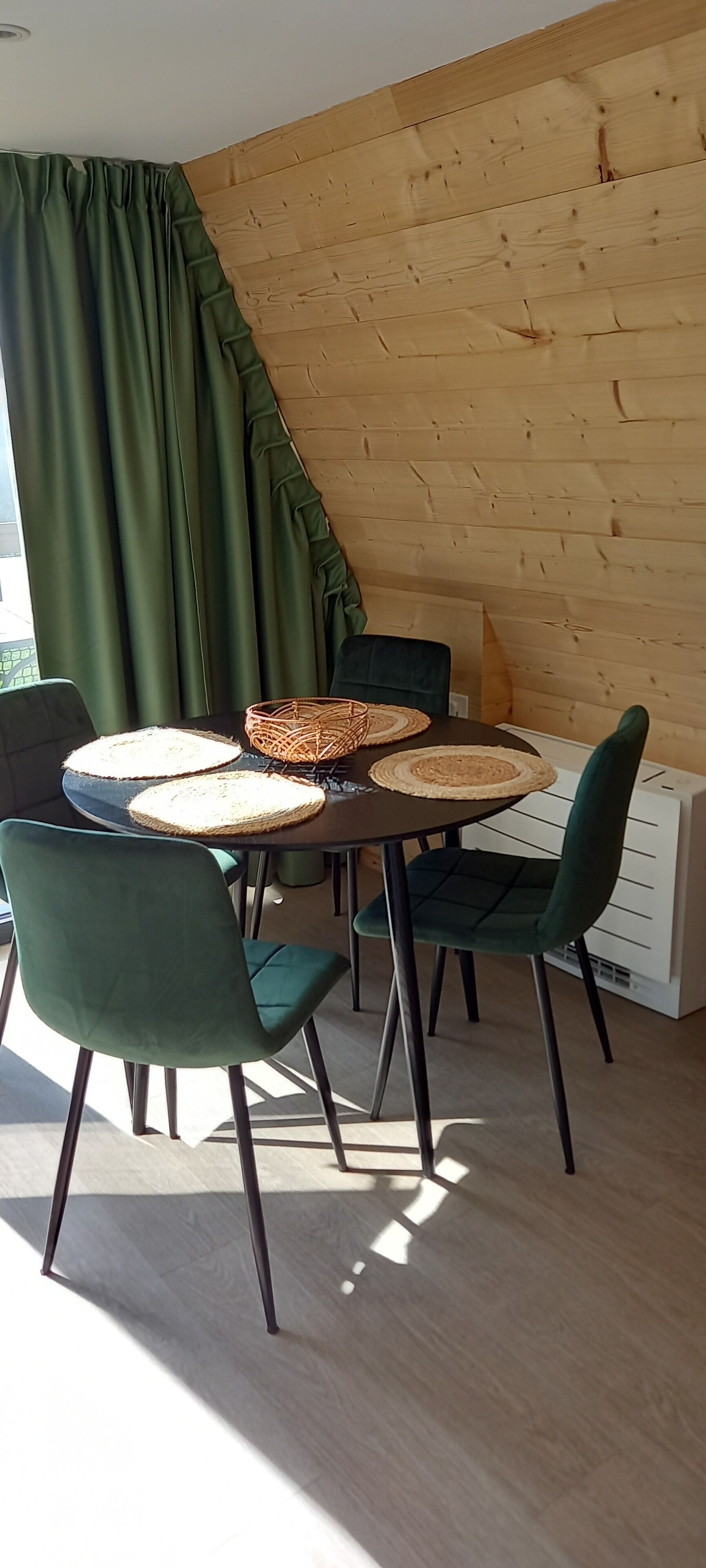 Een eethoek met een ronde tafel, twee stoelen en een geweven placemat.