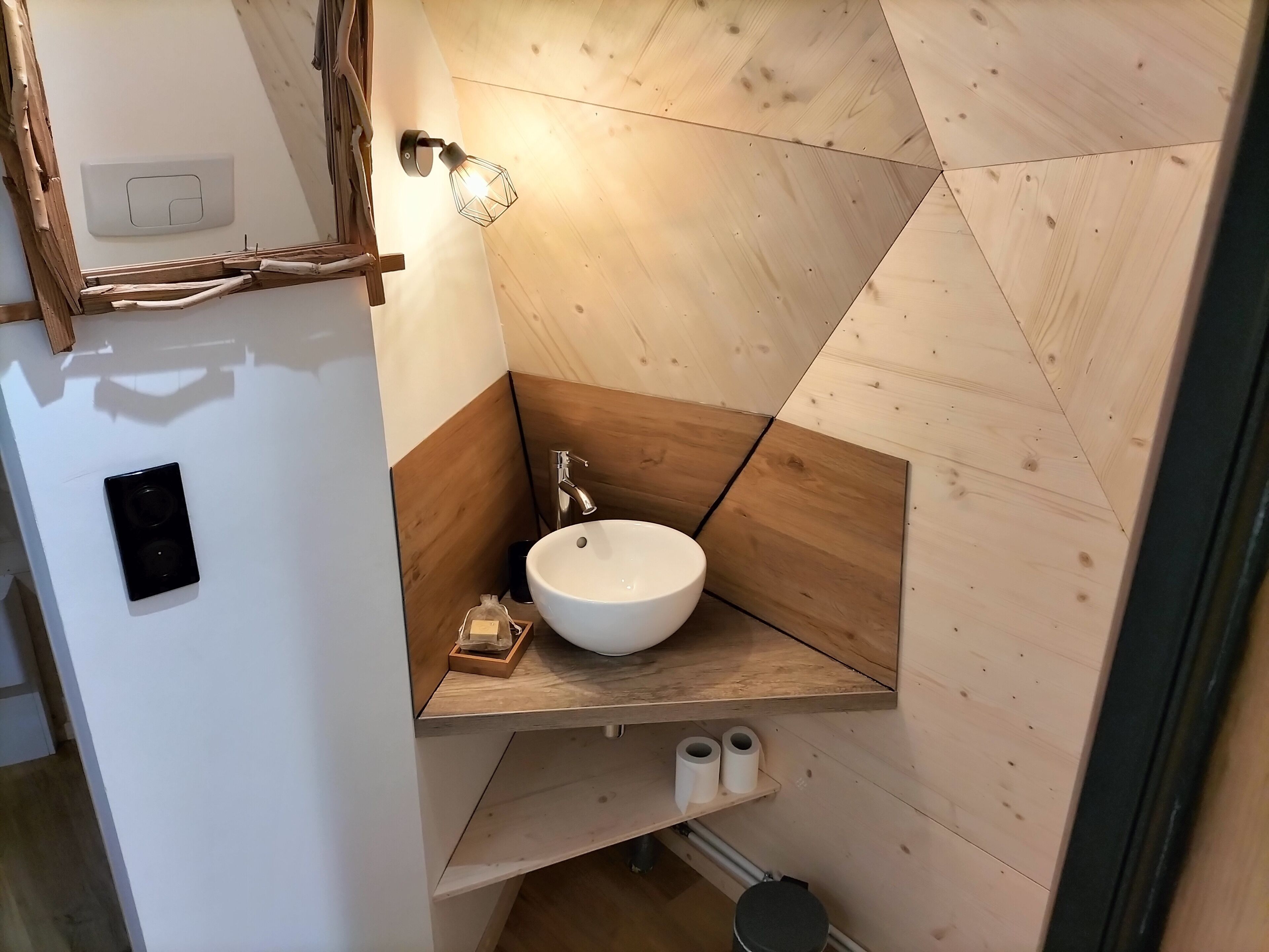 A bathroom with a white sink, wooden accents, a towel rack, and a wall-mounted light fixture.