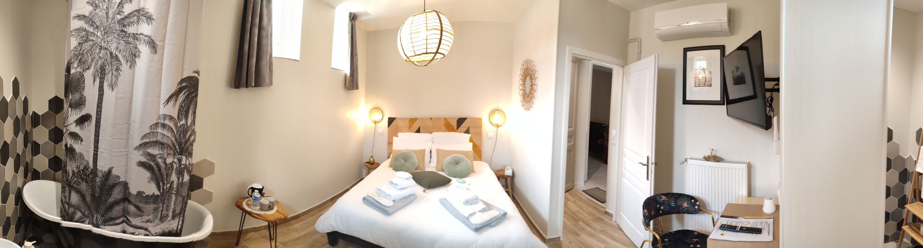A hotel room with a bed, bedside table, and a view of the hallway.