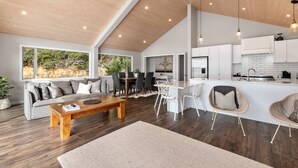 A modern living space with a dining area, kitchen, and large windows offering views of the outdoors. - Seaside Serenity - Kerikeri Holiday Home (Kerikeri)