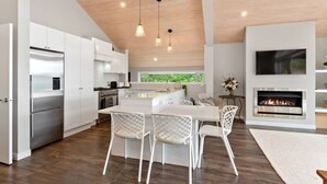 A modern kitchen with white cabinets, stainless steel appliances, and a central island with chairs. - Seaside Serenity - Kerikeri Holiday Home (Kerikeri)