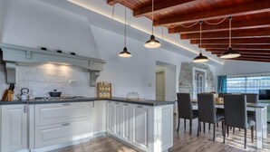 Cozinha moderna com armários brancos, ilha central e iluminação pendente.