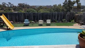 En trädgård med en pool, en rutschkana och utemöbler.
