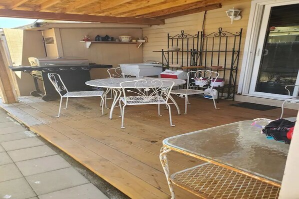 A covered patio with a grill, white metal chairs, and a table. - Cheerful,quiet, 2bd 1 bath home + patio, pool, , walk to beach (Oceanside)