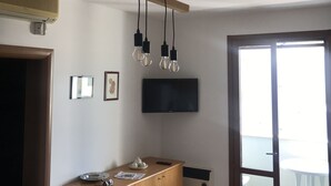 Ett modernt kök med en bänkskiva i trä, en inbyggd spis och en platt-TV som är monterad på väggen.