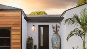 Een modern huis met een houten garage deur, een donkere voordeur en een grote decoratieve vaas.