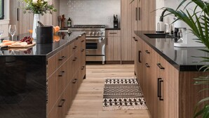 Een moderne keuken met houten kastjes, een zwart aanrecht en roestvrijstalen apparatuur.