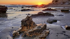 A beach with rocks and a sunset.