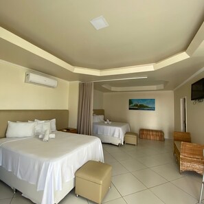 A hotel room with two beds, a small seating area, and a painting on the wall.