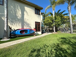 A house with a blue kayak on the porch, a clear sky, and palm trees.