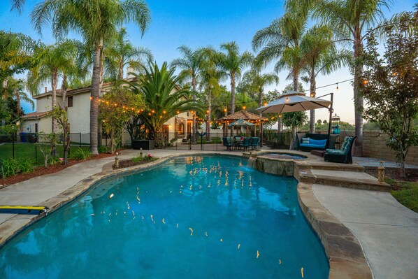 A swimming pool surrounded by palm trees and outdoor furniture.