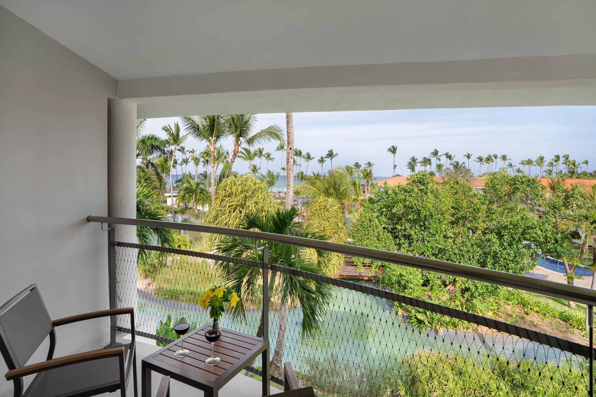 A balcony with a view of palm trees and a body of water.