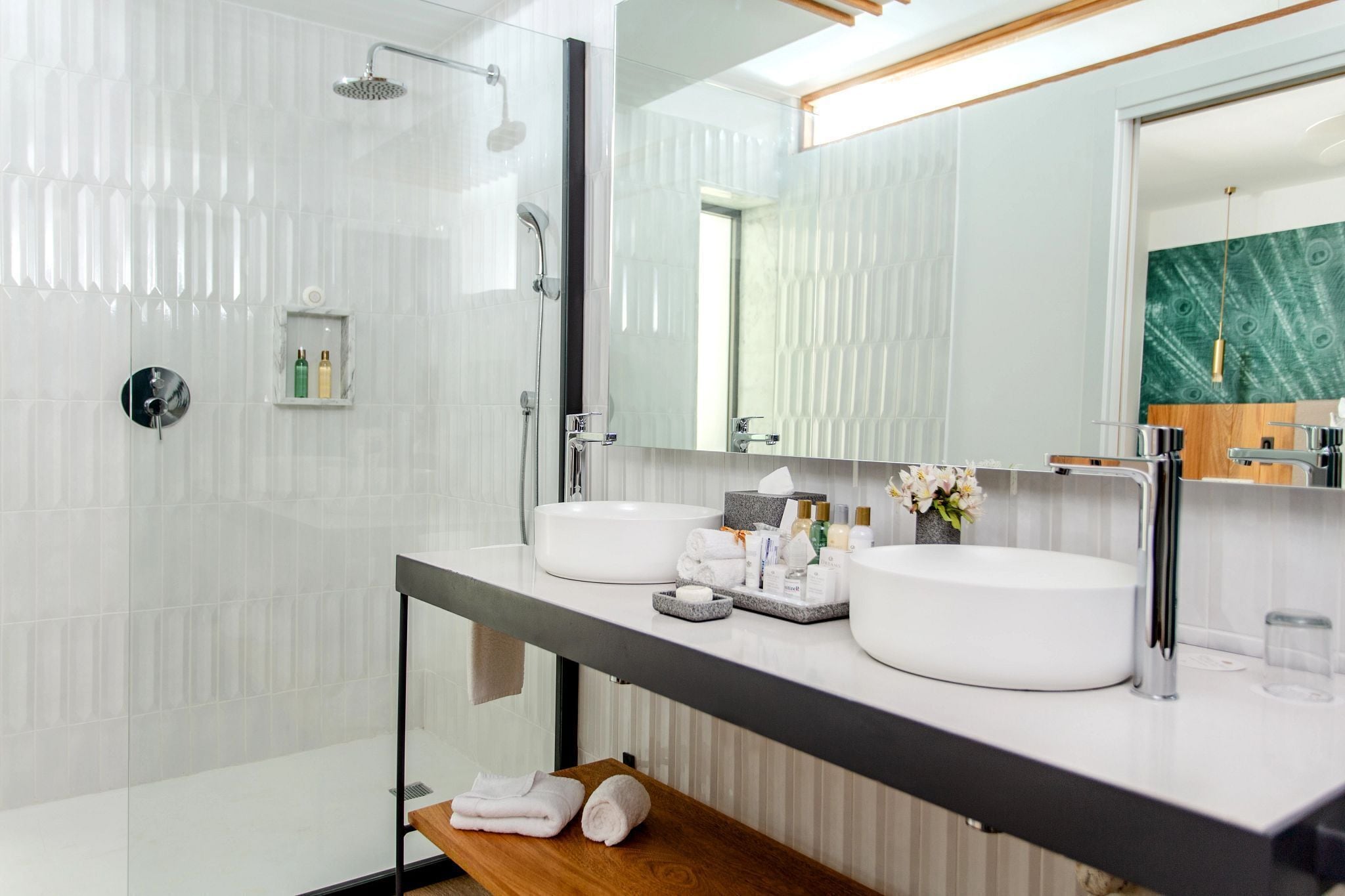 Un baño moderno con dos lavamanos, ducha y un espejo grande.